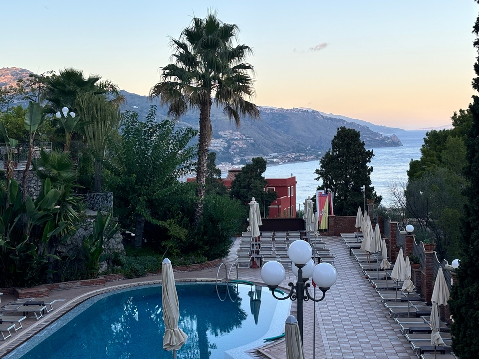 Poolside view with ocean and mountain landscape.