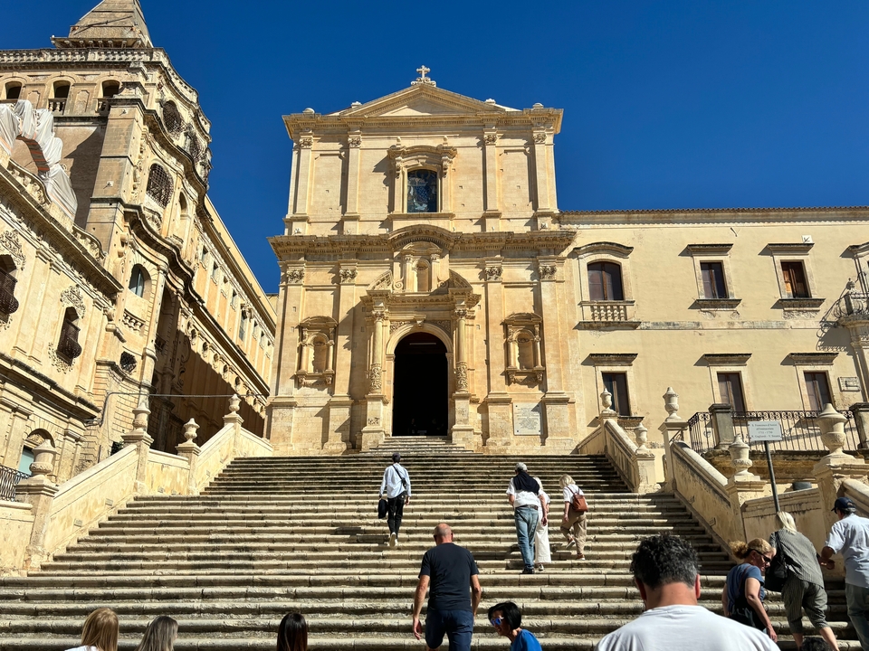People climbing steps to a large historic building.