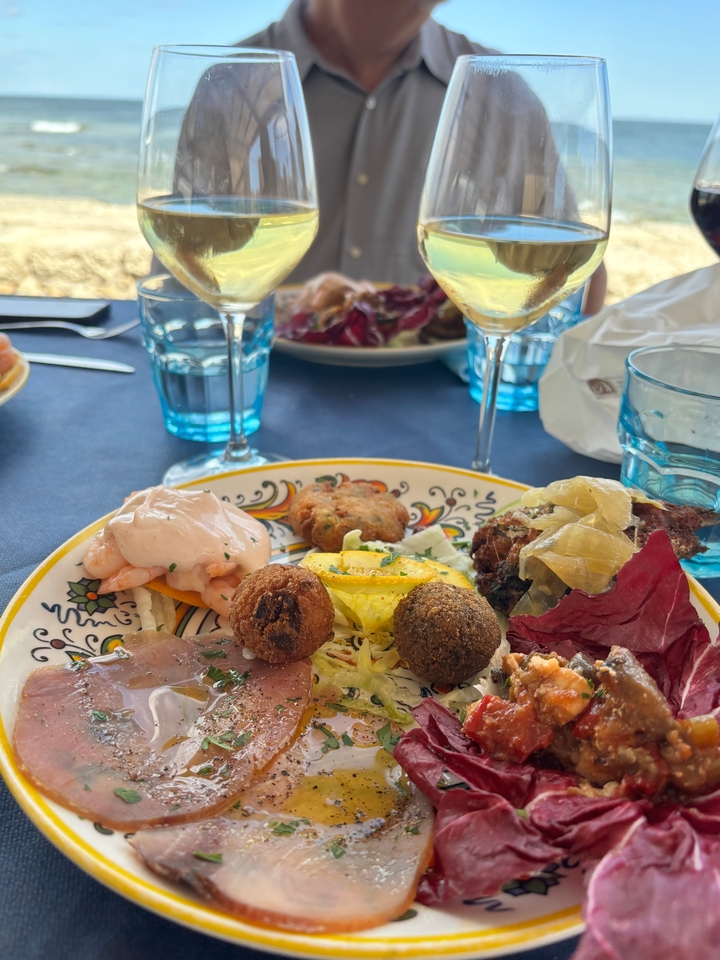 Close-up of a plate with assorted foods and glasses of wine.