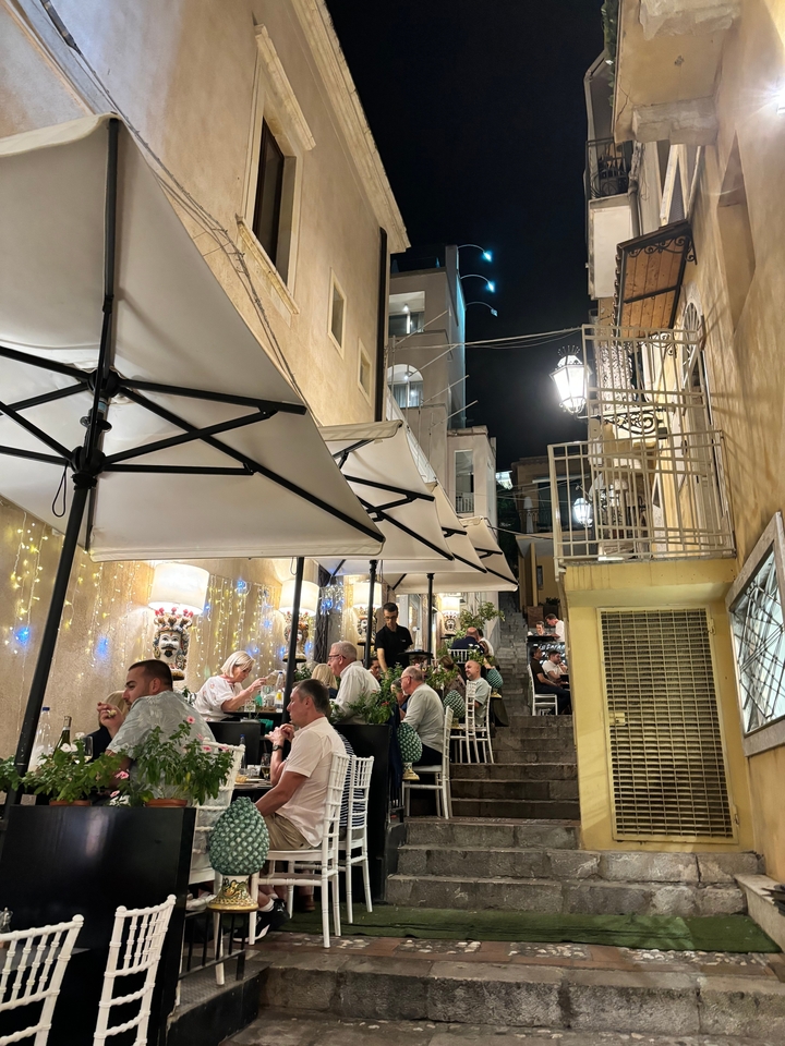 Outdoor dining along a narrow street at night.
