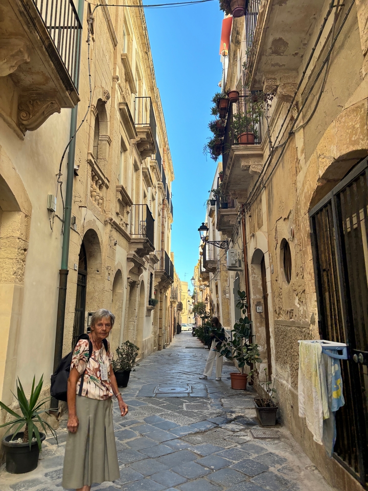 Narrow street with old buildings and a person walking.