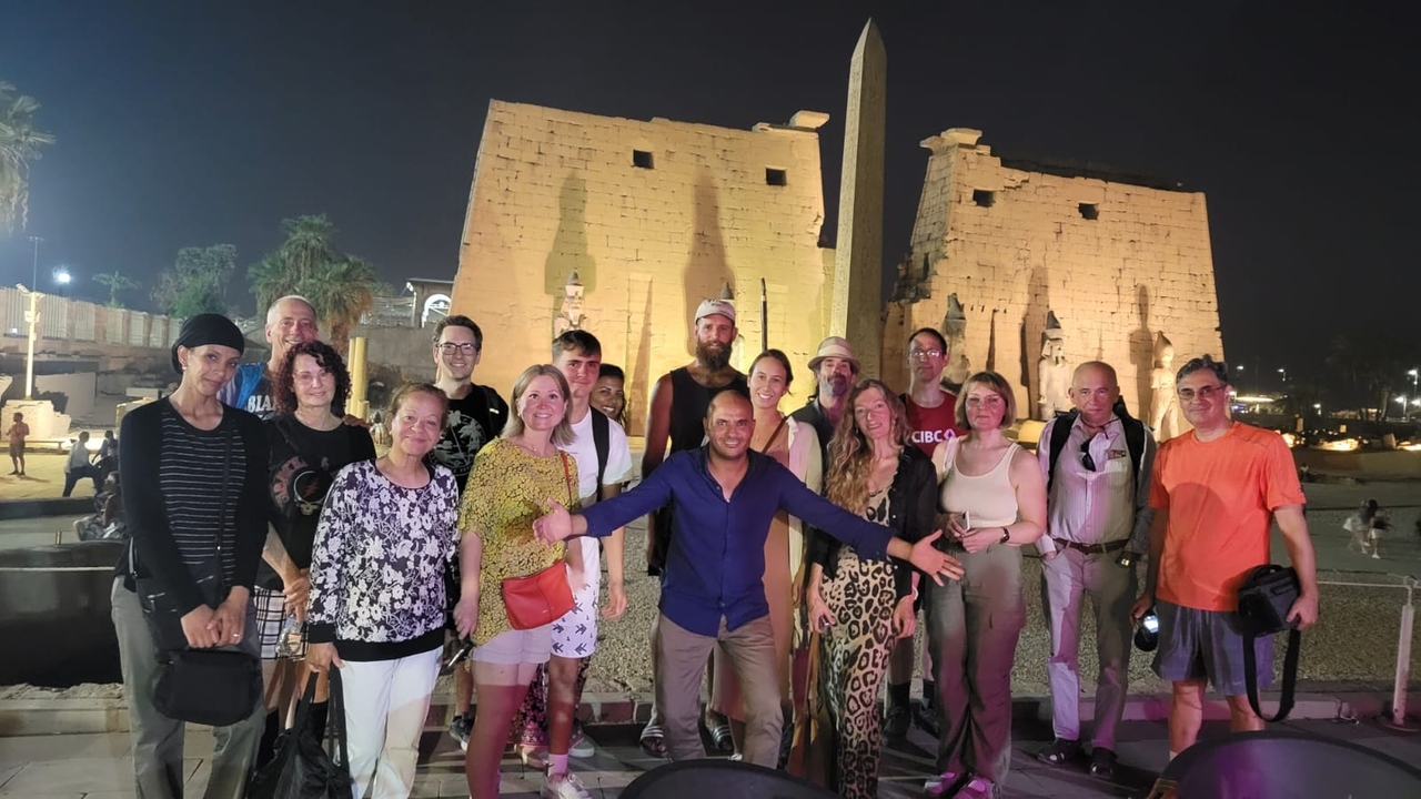 A group of people posing in front of ancient ruins illuminated at night.