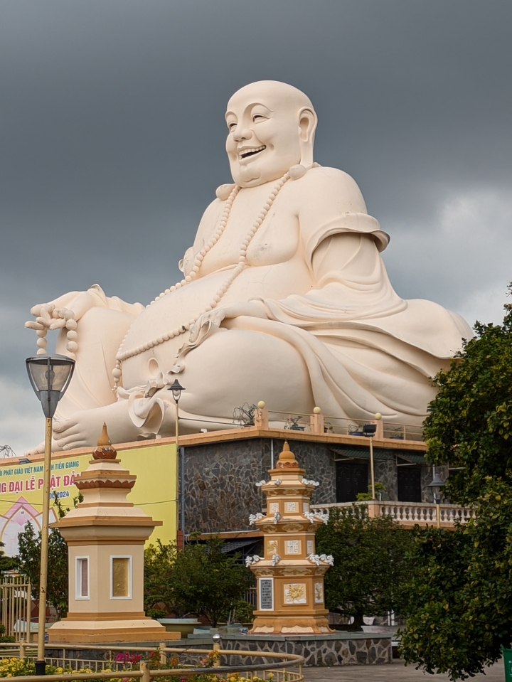 Large statue of a seated Buddha against a cloudy sky.