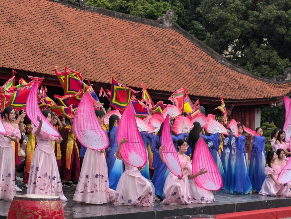 Festival scene with people in traditional costumes holding fans and flags.