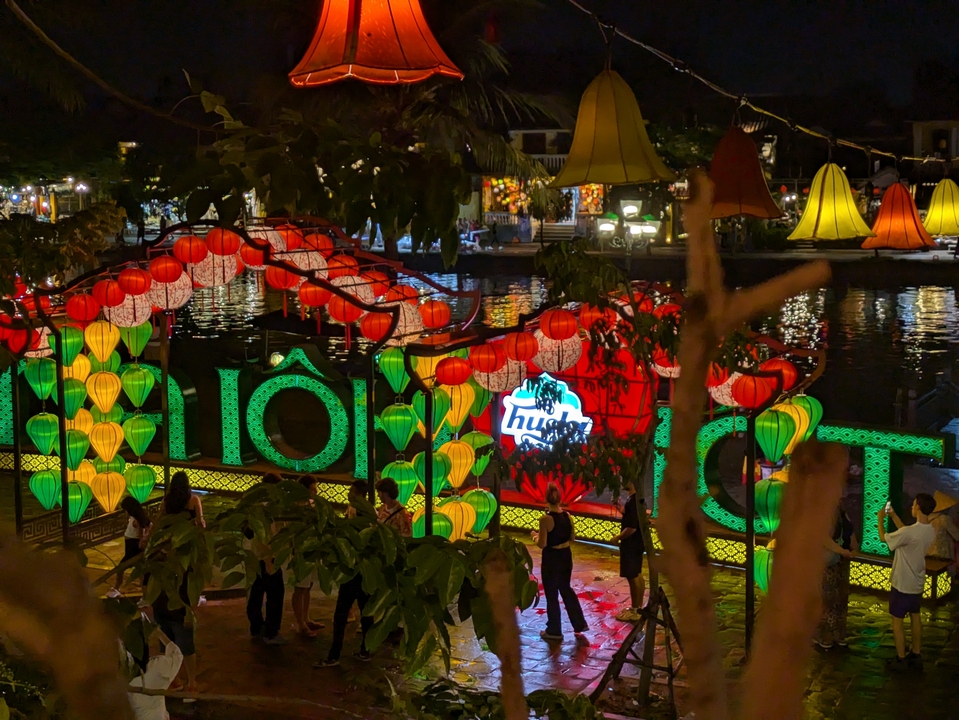 Colorful lanterns and signage with a reflection in water at night.