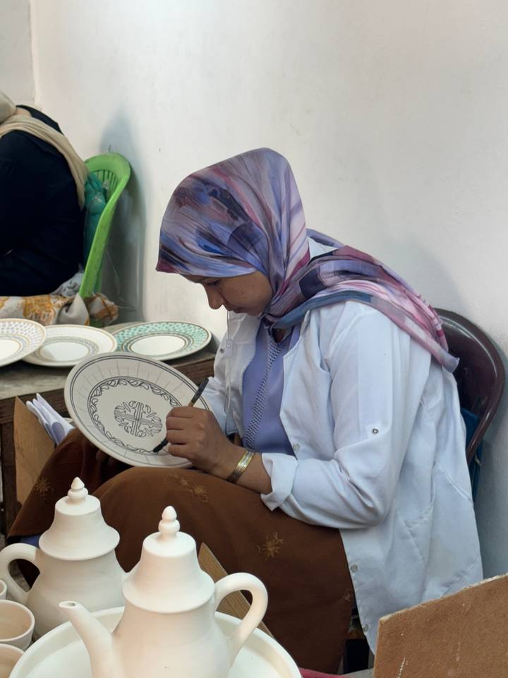Femme concentrée sur la peinture d'une assiette dans un atelier.