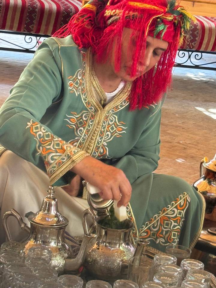 Personne en tenue traditionnelle versant le thé.