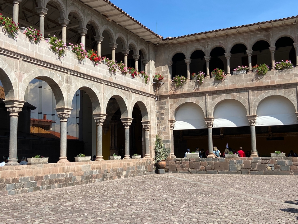 Cour avec arches de pierre et fleurs en pot.