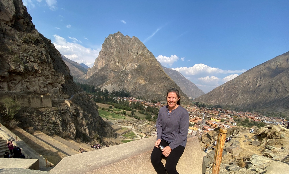 Personne qui pose à Ollantaytambo avec un arrière-plan montagneux.