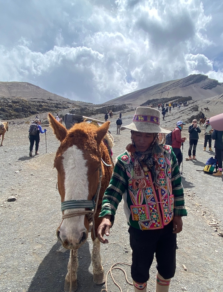 Personne avec un cheval sur un sentier de montagne.