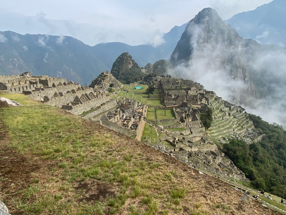 Ruines du Machu Picchu avec des collines luxuriantes et un ciel nuageux.