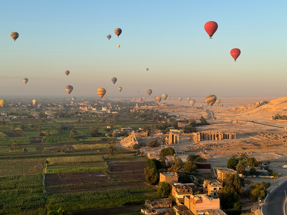 Hot air balloons flying over a landscape with historical ruins