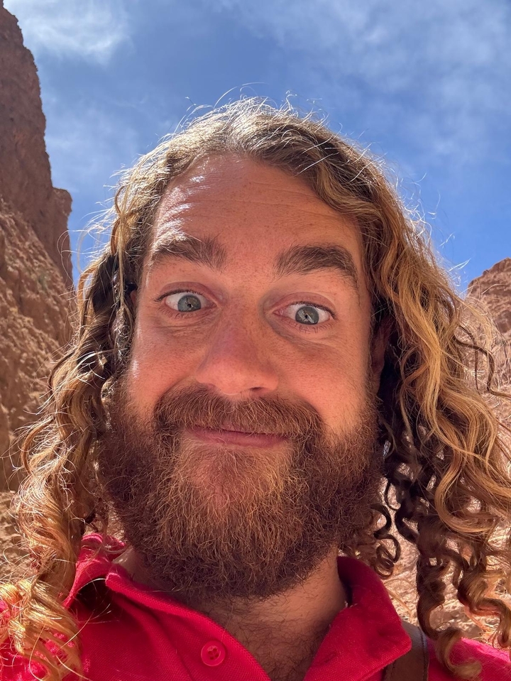 Portrait en gros plan d'un homme avec des falaises en arrière-plan.