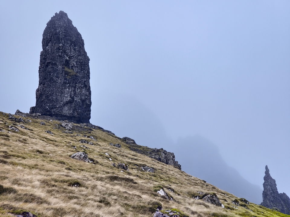 Tall rock formation under cloudy skies.