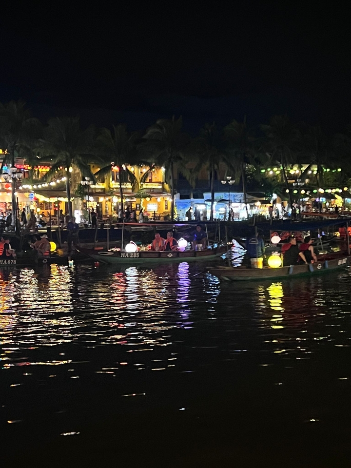 Boats on a river at night, illuminated by lanterns.