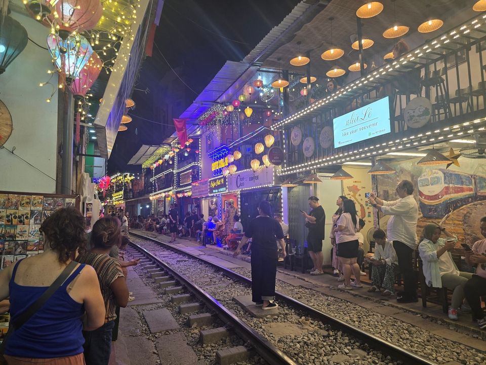 People enjoying a night street market with railway tracks.