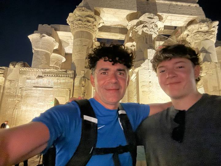 Deux personnes devant une structure ancienne bien éclairée.