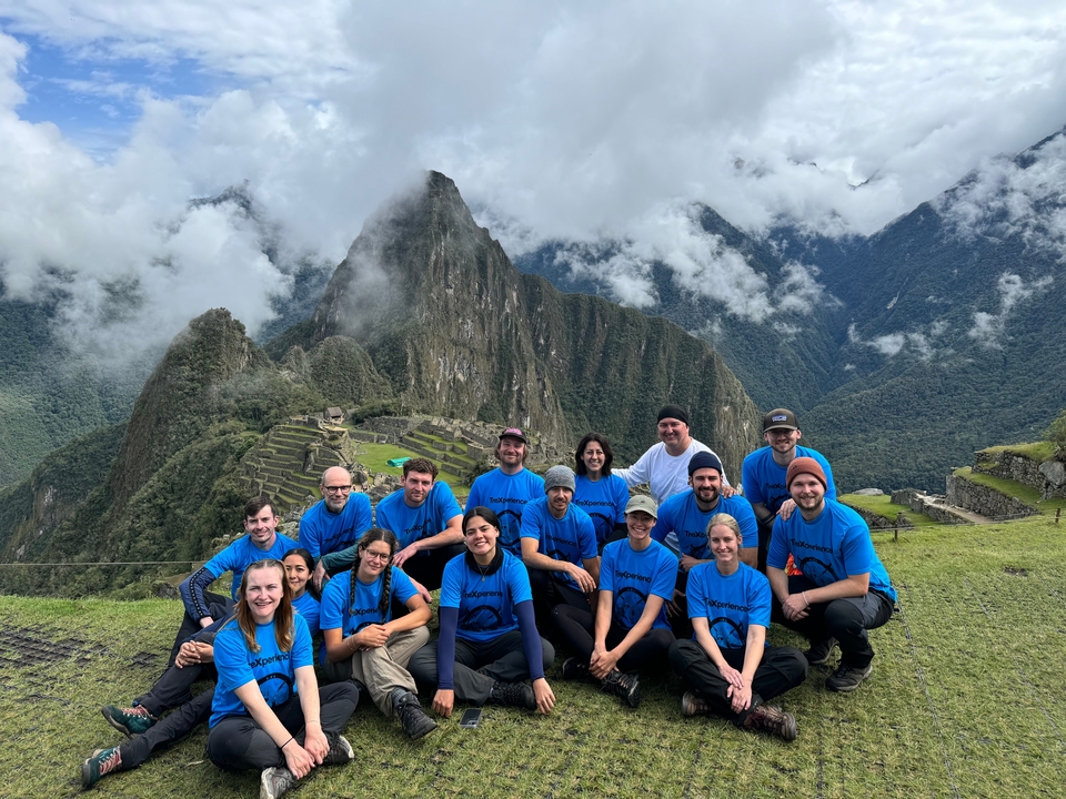 Group of tourists posing with Machu Picchu ruins in the background.