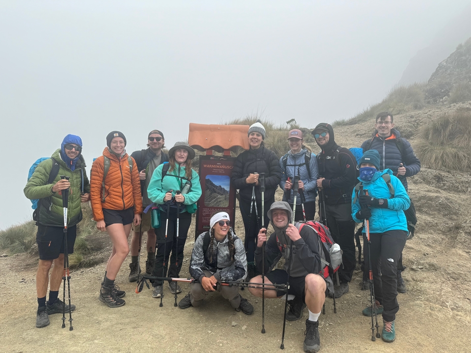 Group of hikers posing at a foggy mountain peak.