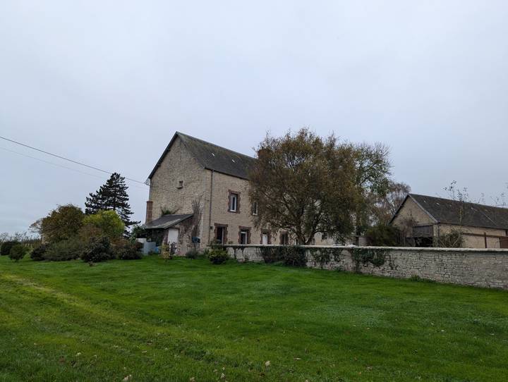 Maison en pierre avec un environnement herbeux par temps nuageux
