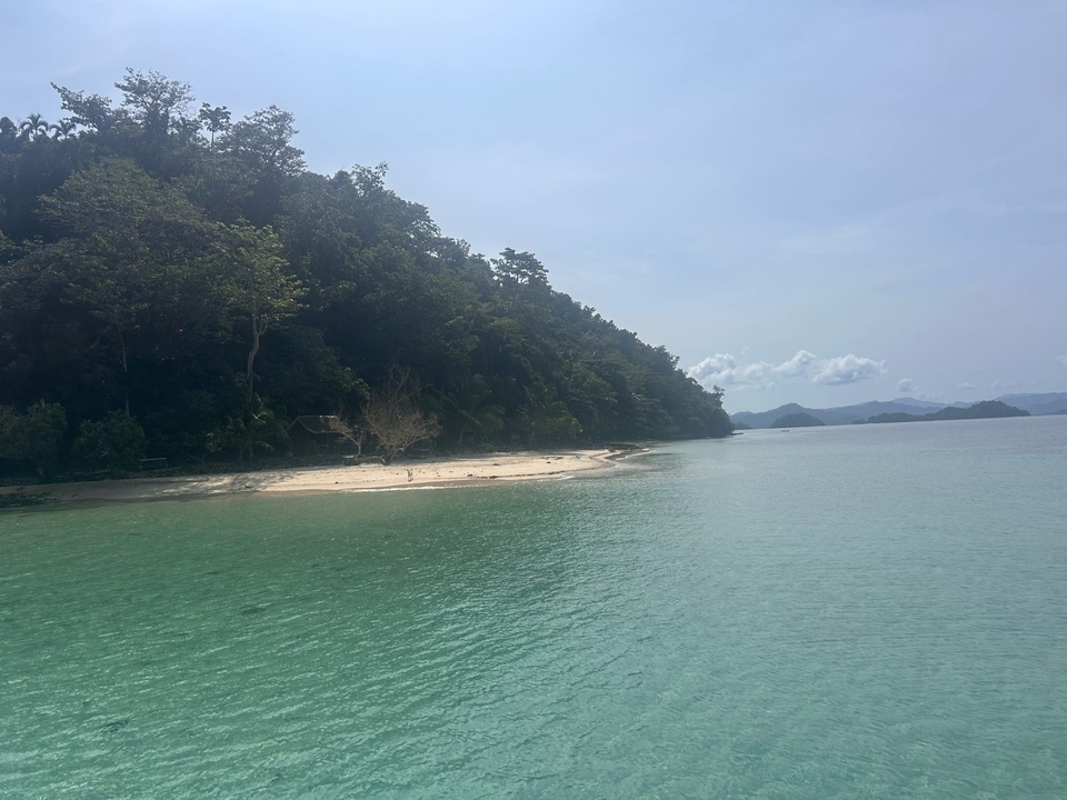 Plage isolée avec du sable blanc et une eau turquoise.