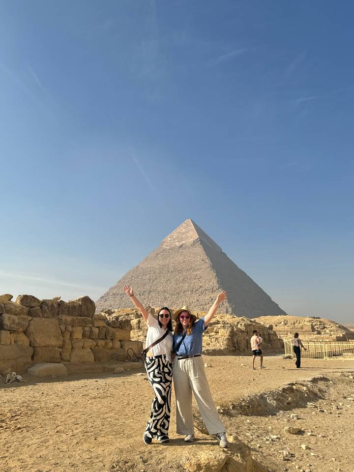 Two people joyfully posing before a pyramid.