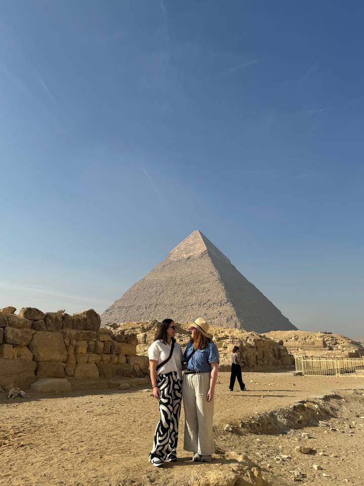 Two people posing in front of a pyramid.