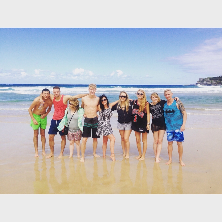 Group of people posing together at a beach with waves in the background.