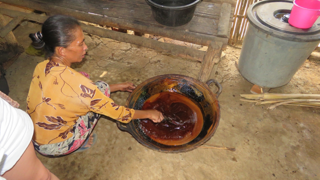 Local woman cooking a traditional dish in a large pot