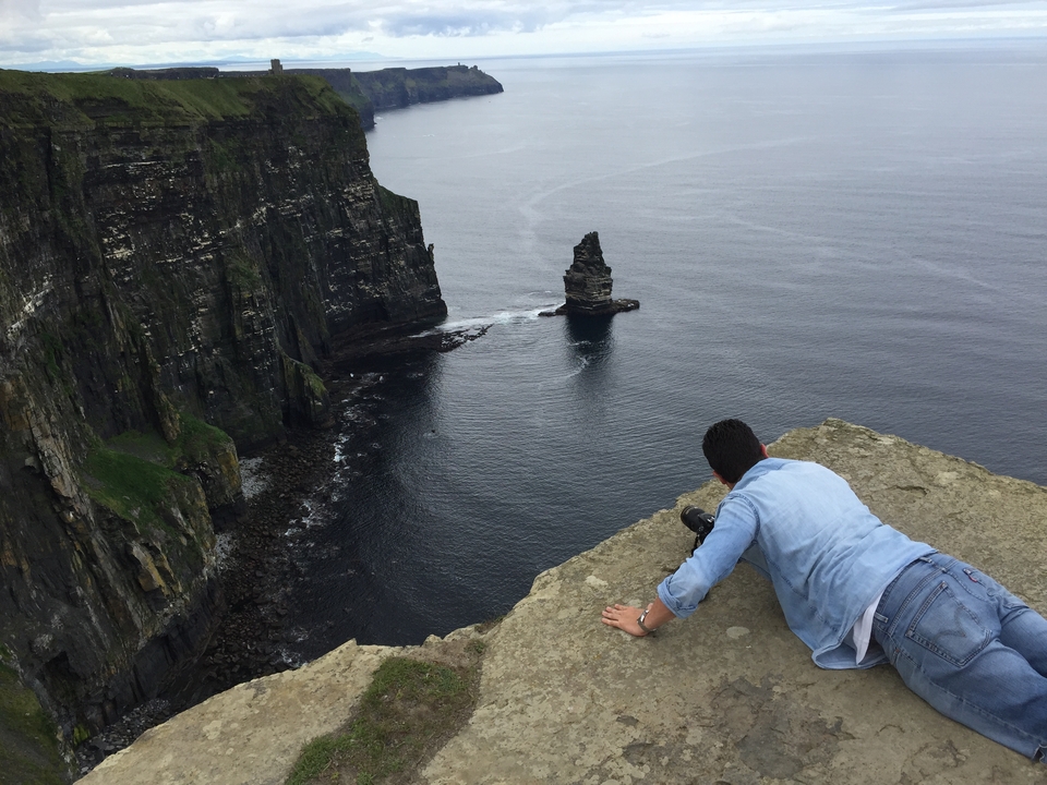 Personne allongée au bord d'une falaise surplombant la mer