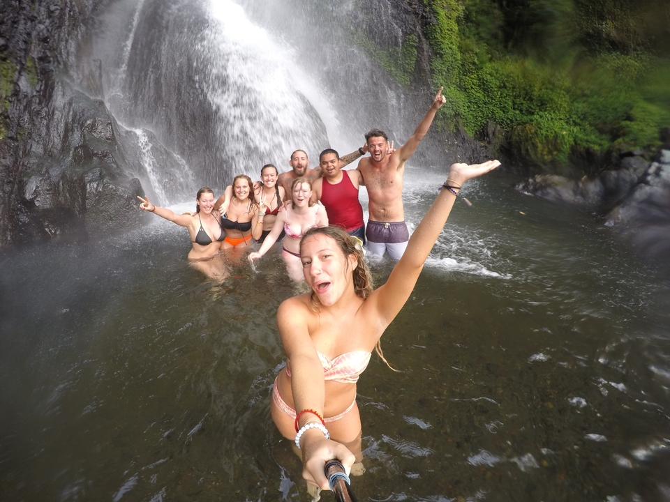 Group of people swimming in a waterfall pool