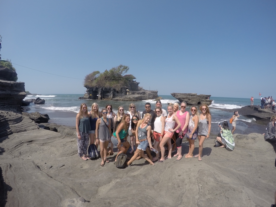 Group of people posing by the sea with rocky cliffs