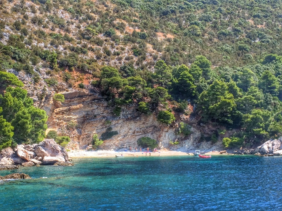 Secluded beach with clear water and rocky cliffs.