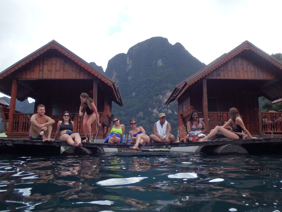 Group of people relaxing by floating bungalows on a lake.