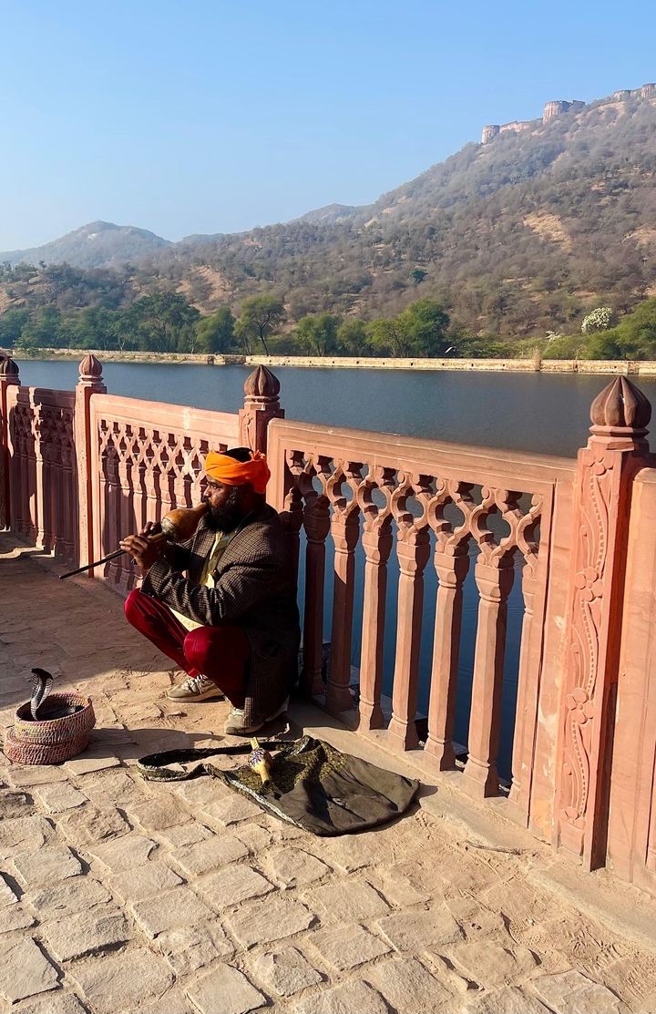Un homme en tenue traditionnelle jouant d'un instrument au bord d'une rivière.