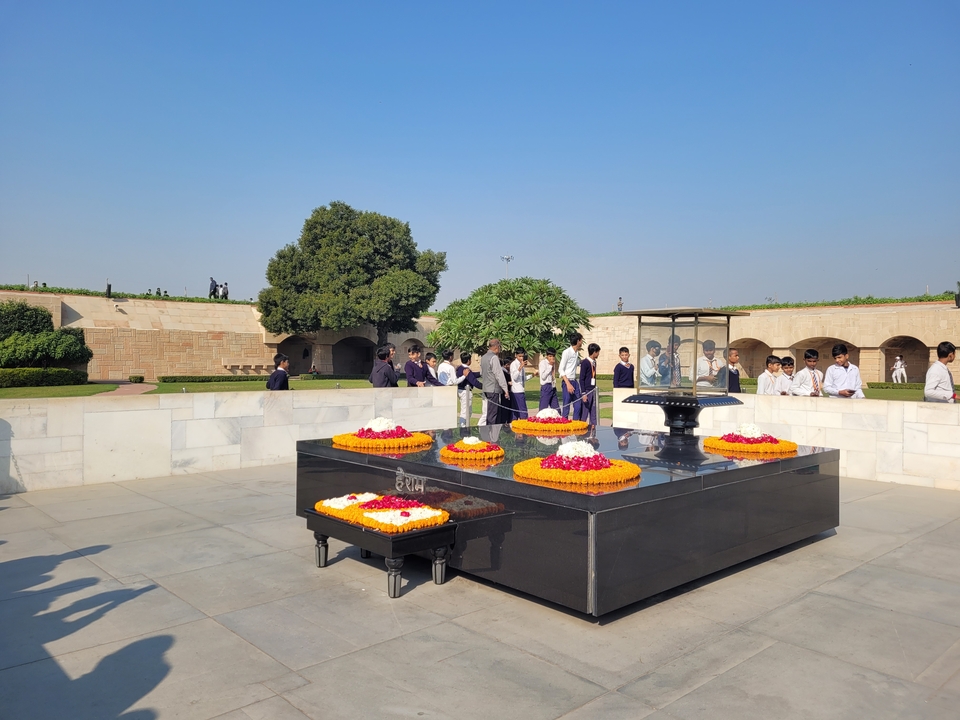 Un groupe de personnes rassemblées autour d'un mémorial avec un jardin en arrière-plan.