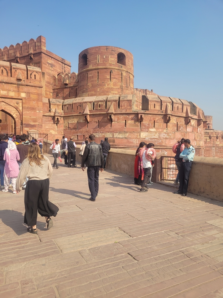 Des visiteurs se promenant le long d'un fort historique aux murs de grès rouge.