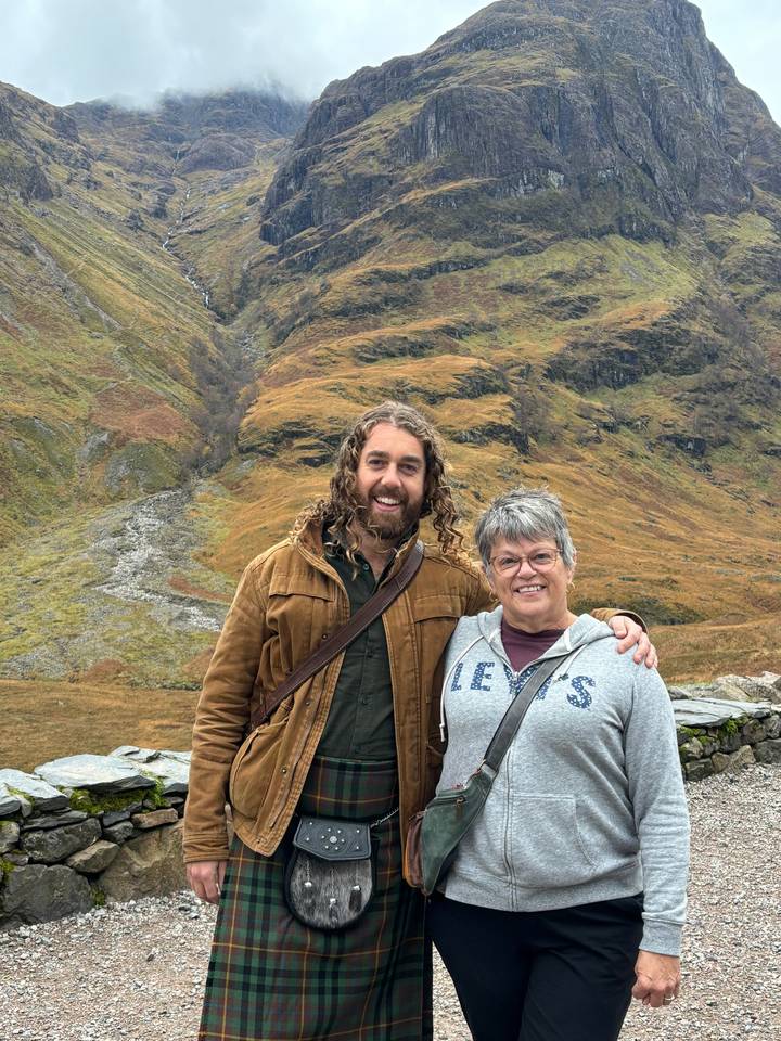 Two people standing in a scenic mountain landscape.