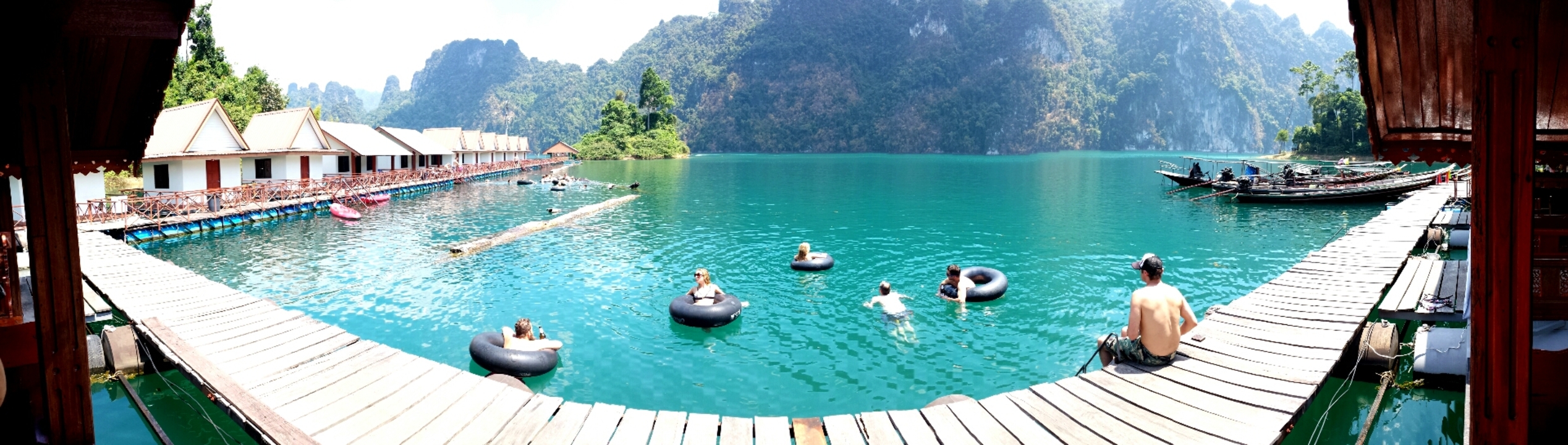People floating in a turquoise lake surrounded by mountains.