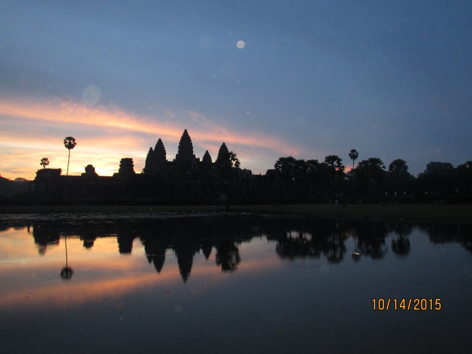 Silhouette d'un temple au coucher du soleil se reflétant dans l'eau.
