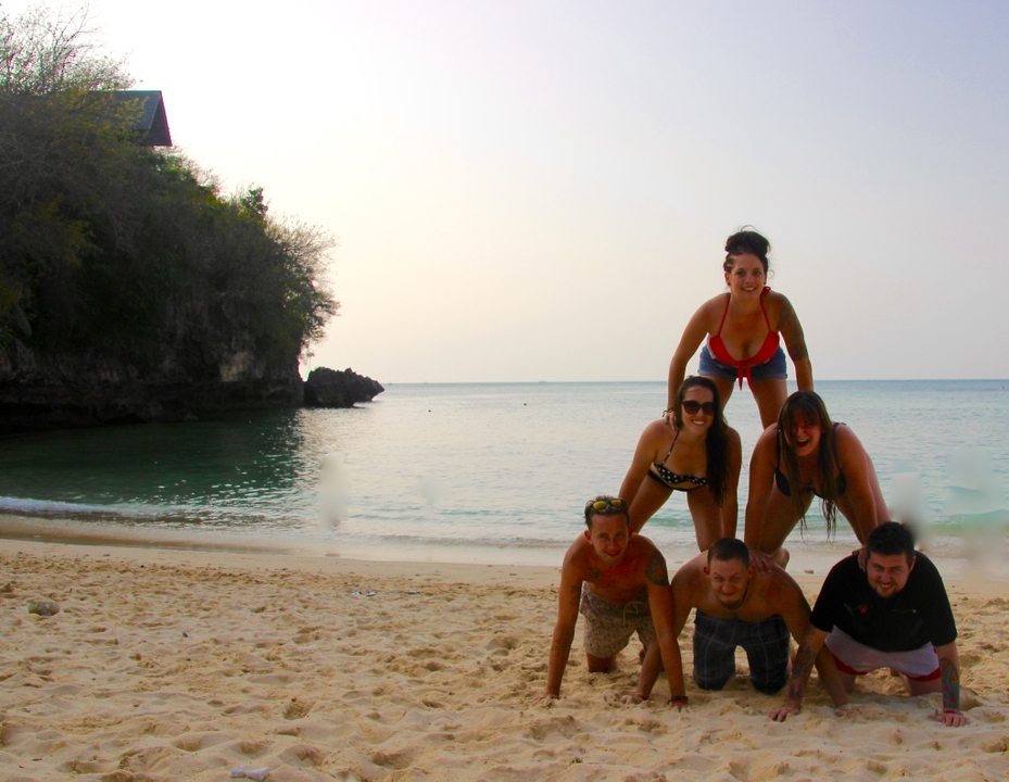 Group of people forming a human pyramid on the beach.
