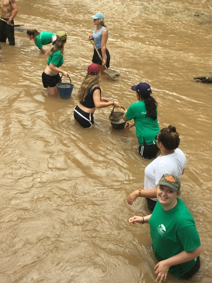 People wading in water carrying buckets.