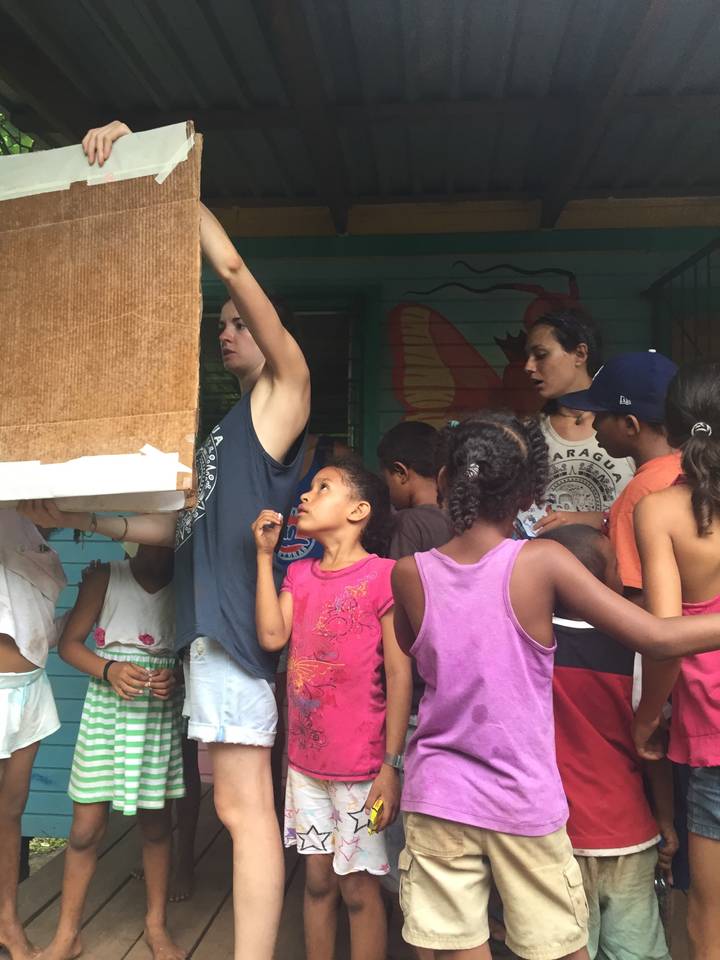 People gathered indoors, looking at something being held up.