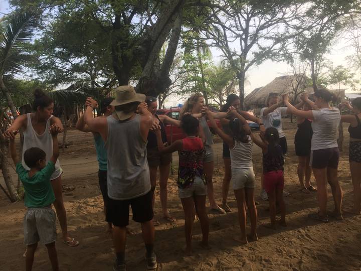 People and children standing in a circle, holding hands.