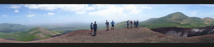 People standing on a rocky hill overlooking a vast landscape.