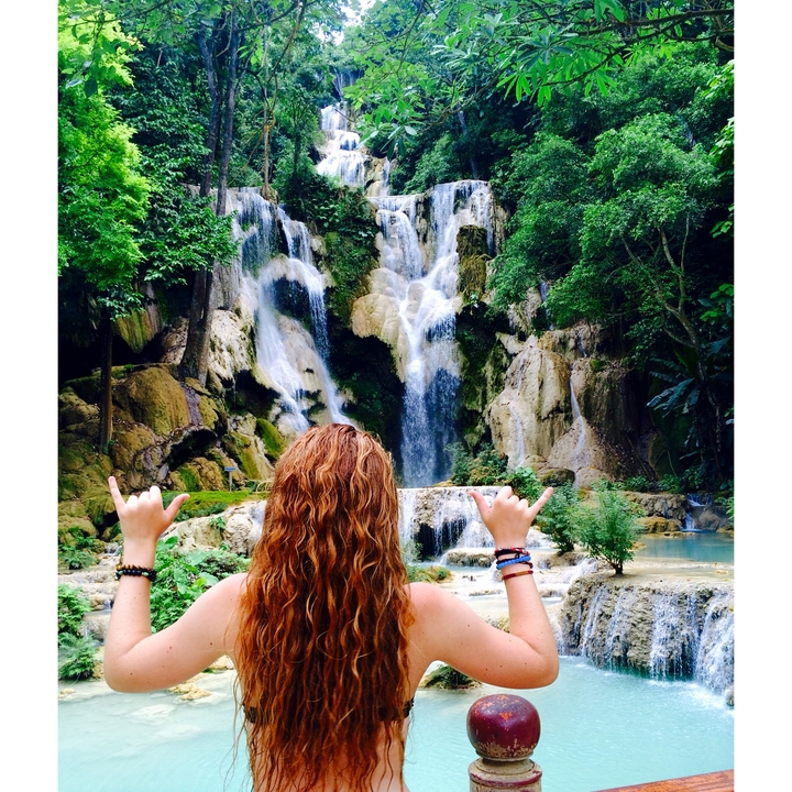Person with hands raised in front of a cascading waterfall.