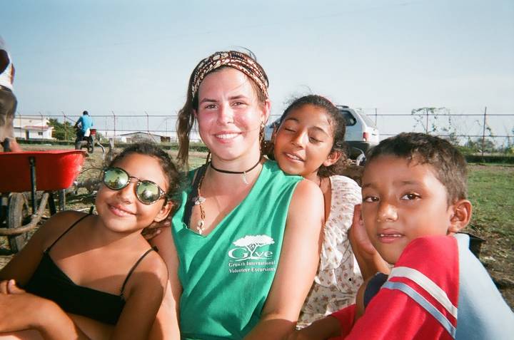 Woman with children in an outdoor setting, smiling.