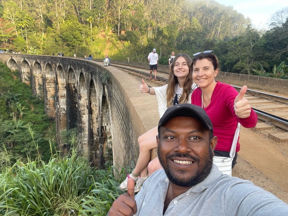 Des gens qui posent sur un pont de chemin de fer.