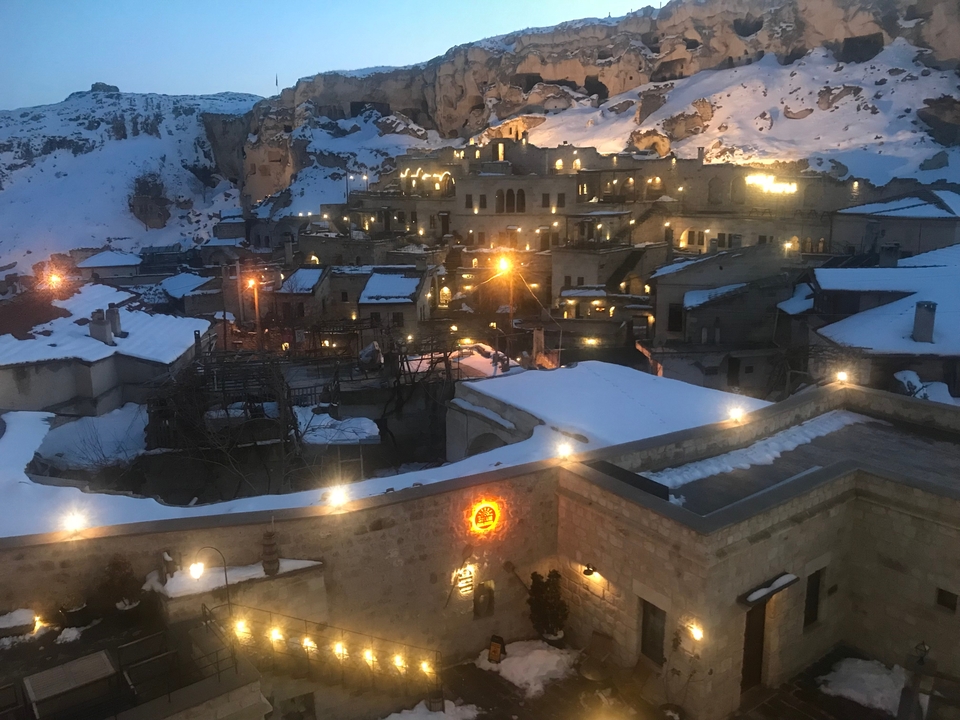 Cityscape of Cappadocia with lit buildings and snow at dusk.
