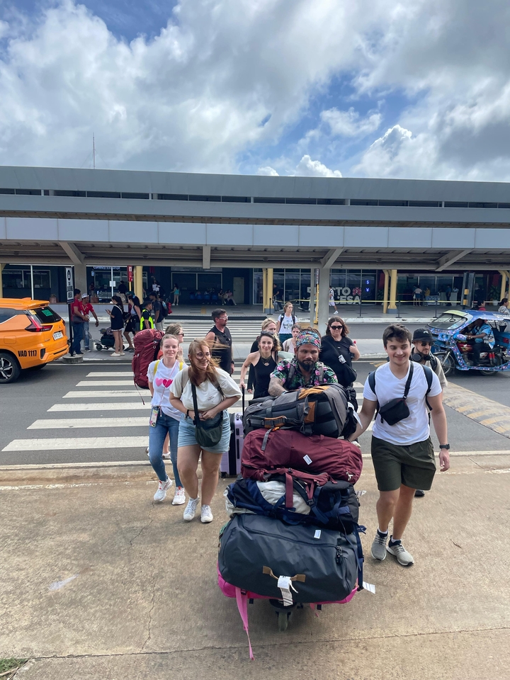 Groupe de personnes portant des bagages devant un bâtiment